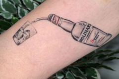 piccolo fineline tattoo di una bottiglia di Sambuca